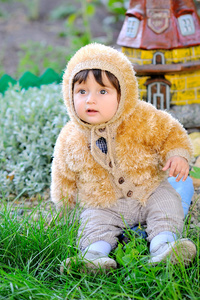 可爱的小宝贝坐在户外活动中秋季夹克的草