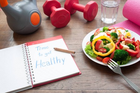 时间得到健康, 在日记本上的文本与沙拉和健身项目在桌子上。美容与节食理念