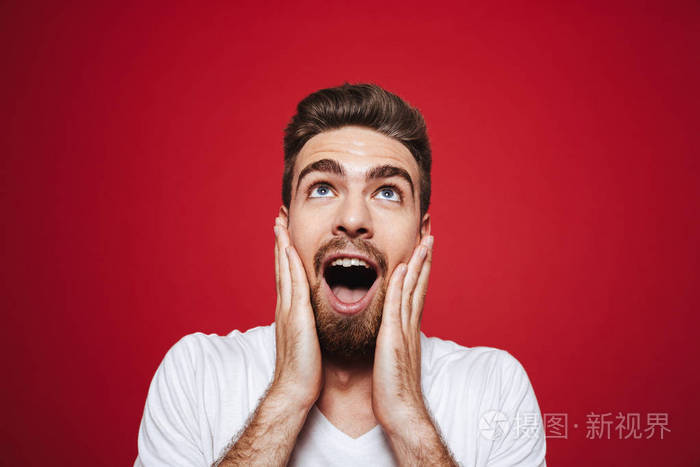 一个兴奋的年轻胡子男子尖叫大声与武器在他的脸上并寻找孤立的白色