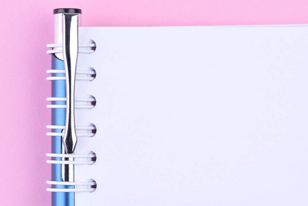 带钢笔的空白便笺纸簿的顶部视图在粉红色背景上