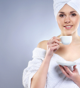 年轻有魅力的女人在毛巾中喝咖啡
