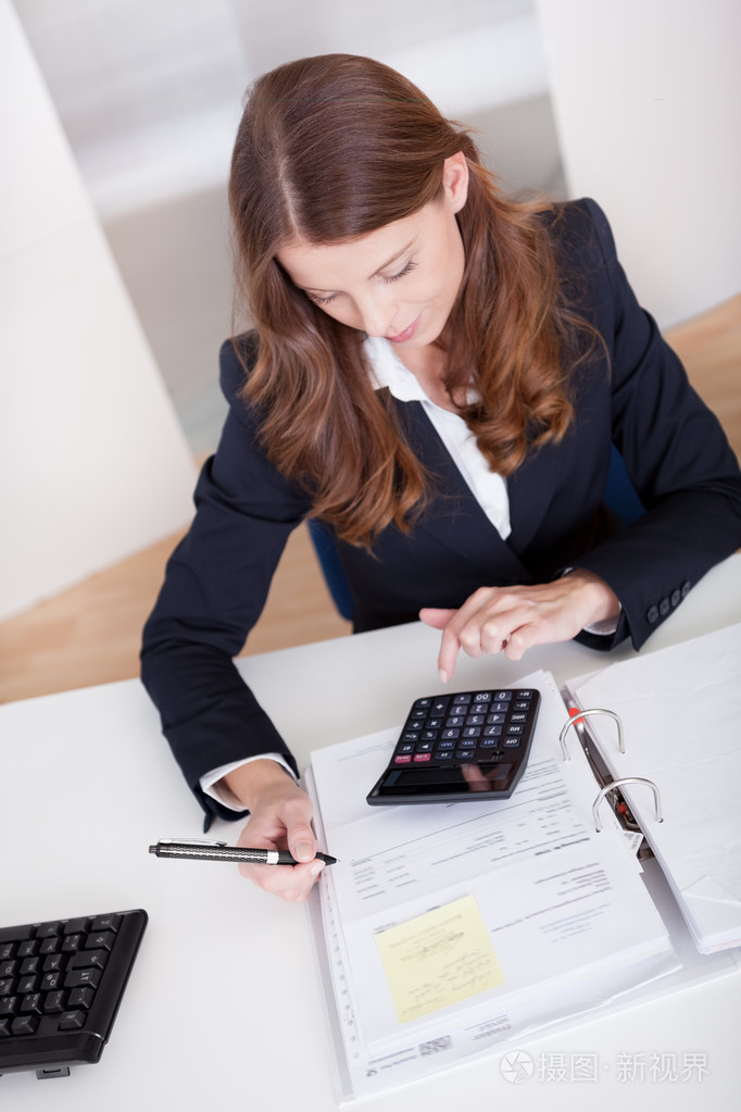 微笑着坐在她的办公桌工作的会计师照片-正版商用图片05iqg7-摄图新