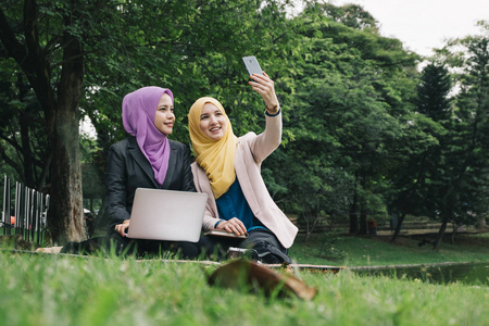 愉快的专业 muslimah 有乐趣, 花费时间在一起和做自拍在城市公园