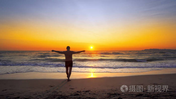 人用手宽开放在空的海洋海滩散步在日落背景下