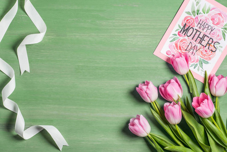 白色丝带的高的看法, 粉红色的郁金香花束和卡片与字母愉快的母亲天在