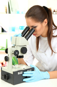 看着显微镜在实验室中的青年科学家
