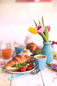 古董照片。一个家庭早餐的牛角面包与芝麻菜, 奶酪和芳香咖啡, 鸡蛋不同的颜色。郁金香花束