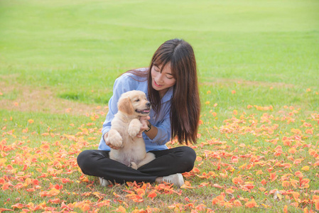 美丽的亚洲女孩微笑与她的小狗在公园里