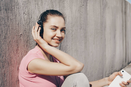 微笑的年轻女孩在粉红色 t恤上听音乐的耳机, 休息后, 慢跑