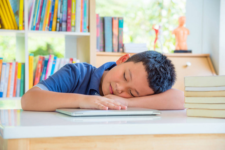 年轻的亚洲小学生在学校图书馆睡着了