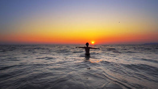 在日落背景, 自由的概念, 在海洋中行走的女人手宽开放照片