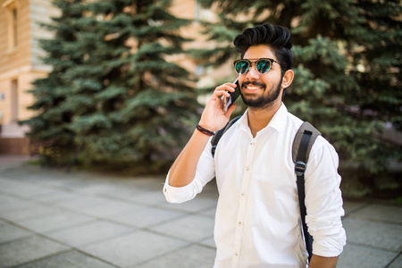 年轻英俊的印度男人谈电话市区内的肖像
