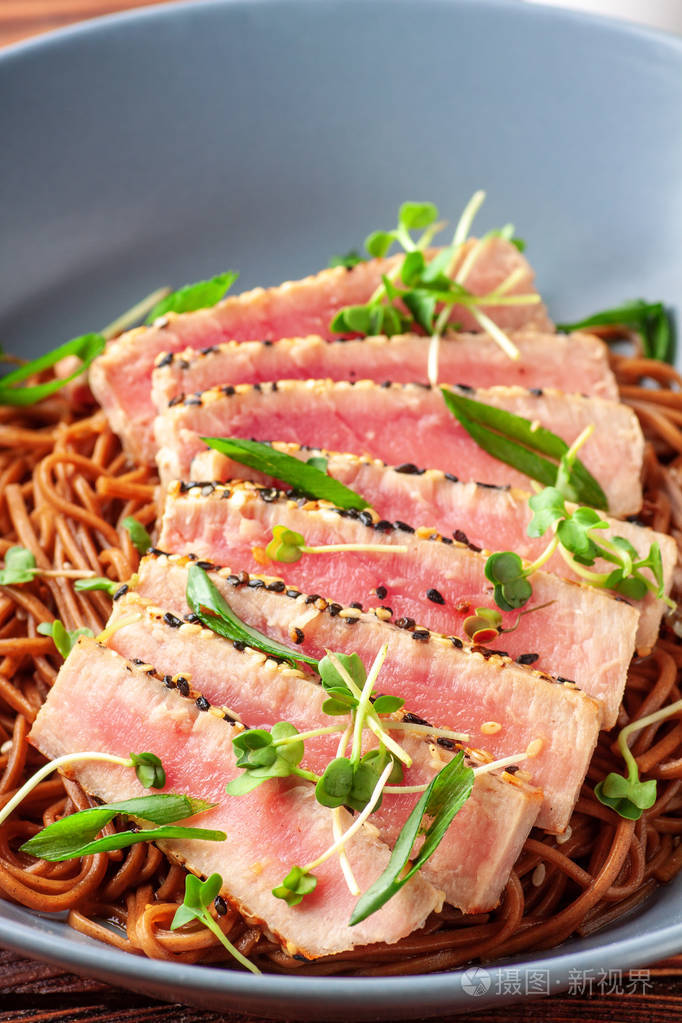 日本荞麦荞麦面用芝麻切片金枪鱼在黑木桌上