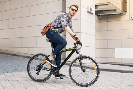 聪明英俊的人骑自行车在城市
