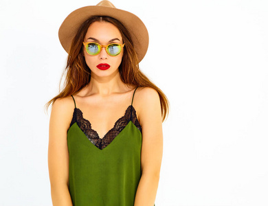 年轻时尚的女孩在休闲夏季绿色的衣服和棕色的帽子, 红色的嘴唇, 在白色的墙壁上摆出