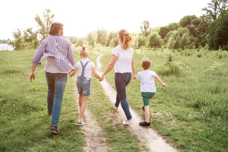 父母们手牵着孩子.他们正在跳跃和享受的时刻照片