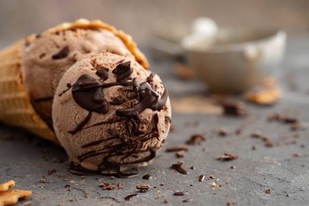 自制的巧克力冰淇淋在华夫饼锥, 用勺子冰淇淋, 可可和黑巧克力片。在一张深灰色的桌子上。复制空间关闭视图