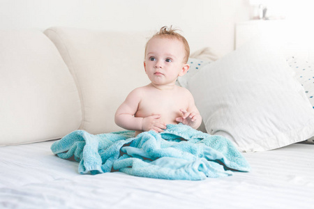 可爱的9月大的小男孩坐在床上洗完澡后