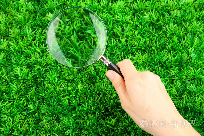 在绿色草地上,手中的放大镜照片-正版商用图片05jow4-摄图新视界