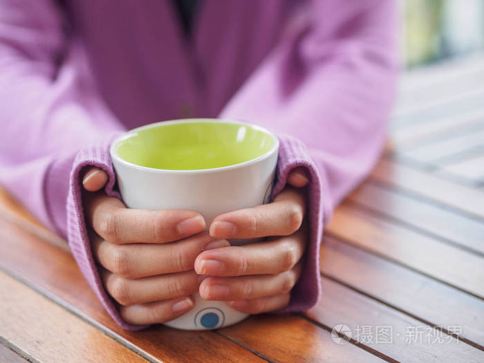 女手拿着杯子在木桌上