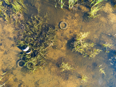 旧汽车轮胎正躺在池塘里。空中摄影