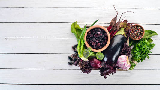 紫色的食物。新鲜蔬菜和浆果在一个木箱里。在一个木质的背景。顶部视图。复制空间