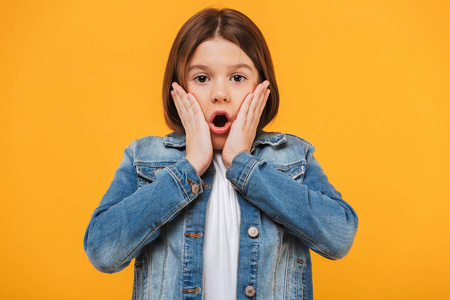 惊讶的青少年女生尖叫一个惊讶的小女生的肖像看着在黄色背景的相机