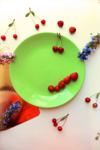 夏天的概念。樱桃和草莓放在绿盘子里。复制空间