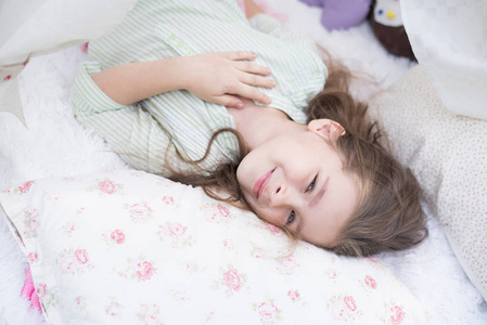 可爱的小女孩醒了在她的床上。可爱的小女孩睡在床上与她的玩具