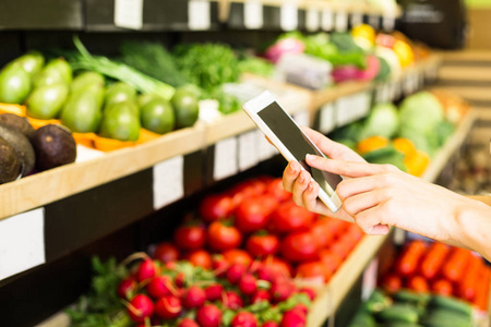 在超市购买产品时使用智能手机的妇女