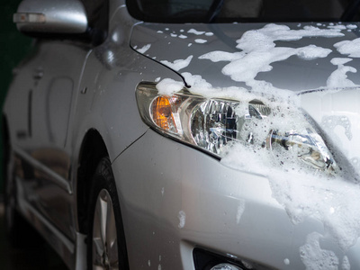 汽车护理店的车身上有白色肥皂的车。洗车理念