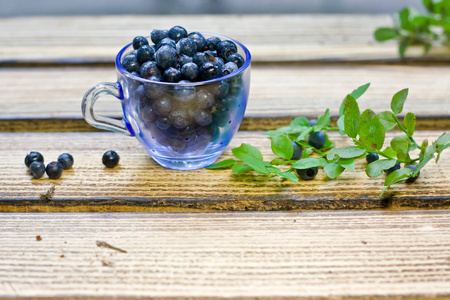 蓝莓浆果躺在厨房的木桌上的杯子里。