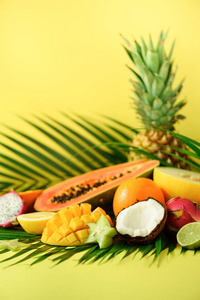 黄色背景下的异国水果品种。排毒, 素食, 夏日概念。木瓜, 芒果, 菠萝, 杨桃, 龙果, 猕猴桃, 橙, 瓜, 椰子, 石灰