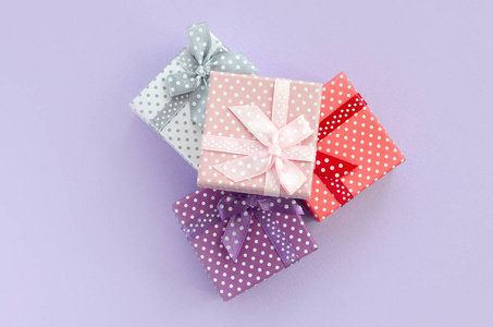 一堆带有丝带的小彩色礼品盒位于紫罗兰色的背景上。简约平躺顶视图