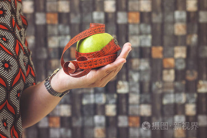 健康快乐的西班牙裔妇女持有苹果和磁带措施的饮食和减肥的概念