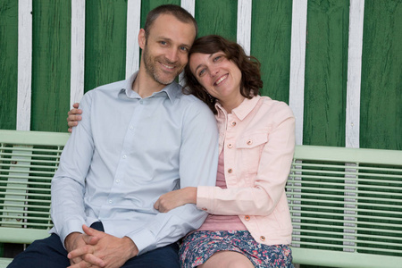 快乐的年轻情侣在公园绿色的长凳上的夏天一天的爱情