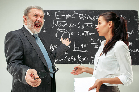 男教授和女青年反对黑板在教室里