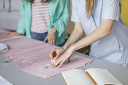 关闭时装设计师在缝纫车间粉色纺织品上用肥皂画画
