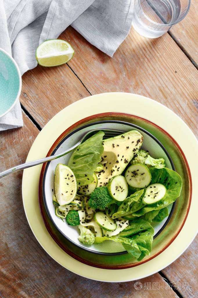 健康素食沙拉的绿色蔬菜在碗上的木桌: 花椰菜, 生菜沙拉, 鳄梨, 西