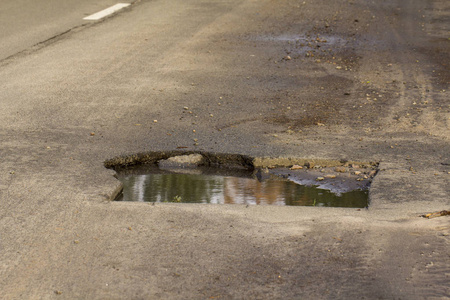 下水道舱口附近的沥青坑, 在街道中间照片