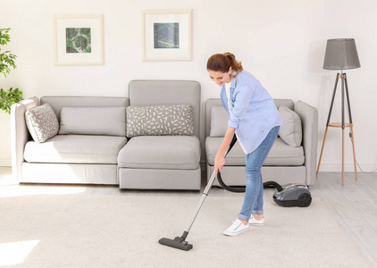 家用吸尘器清理地毯上的污垢的妇女