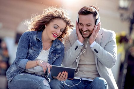 快乐的年轻夫妇有乐趣户外和微笑, 看着笔记本电脑
