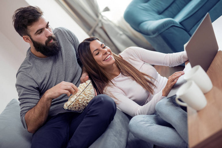 夫妇看电影和吃爆米花在沙发上