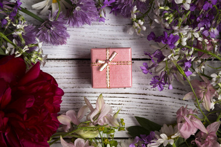 在一个纸板粉红色的盒子, 周围有很多粉红色, 丁香花和红色的礼物。节日礼物