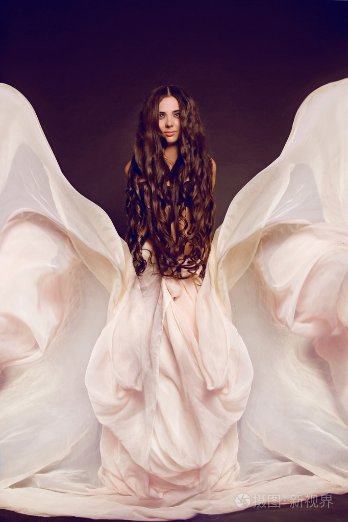 美丽的女孩在飞行,在华丽博士的黑发吹裙子