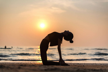 ung frisk kvinna utvar yoga p stranden vid solnedgngen