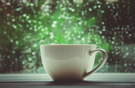 一杯热茶在窗外的背景雨中。选择性聚焦