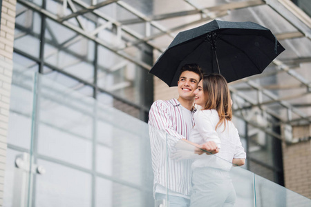 在下雨天, 在城市中心的英俊的人有乐趣.爱和假期概念照片