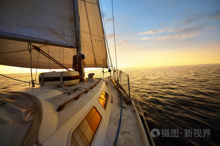从帆帆船甲板上倾斜在一个日落的风