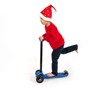 孩子与圣诞帽子和白色背景上的滑板车
